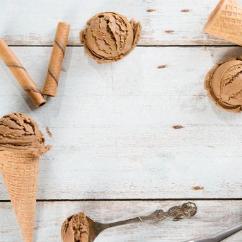 Top view brown ice cream in waffle cone on rustic wooden background. Copy space on middle.