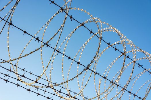 Barbed Wire Fence Used For Protection Purposes Of Property And Imprisonment, No Freedom, Barbed Wire On fence With Blue Sky To Feel Worrying.