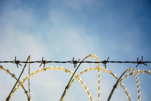 Barbed Wire Fence Used For Protection Purposes Of Property And Imprisonment, No Freedom, Barbed Wire On fence With Blue Sky To Feel Worrying.