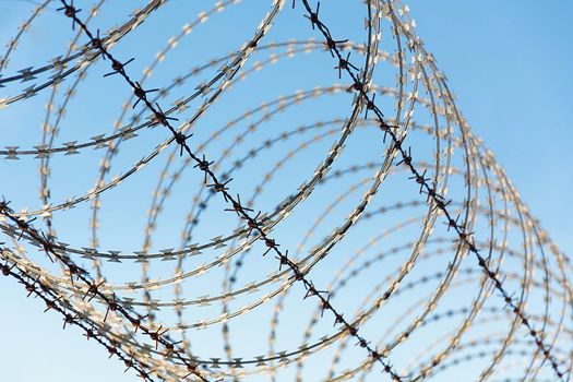 Barbed Wire Fence Used For Protection Purposes Of Property And Imprisonment, No Freedom, Barbed Wire On fence With Blue Sky To Feel Worrying.