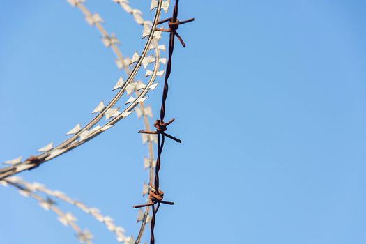 Barbed Wire Fence Used For Protection Purposes Of Property And Imprisonment, No Freedom, Barbed Wire On fence With Blue Sky To Feel Worrying.