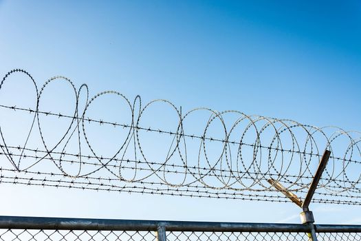 Barbed Wire Fence Used For Protection Purposes Of Property And Imprisonment, No Freedom, Barbed Wire On fence With Blue Sky To Feel Worrying.