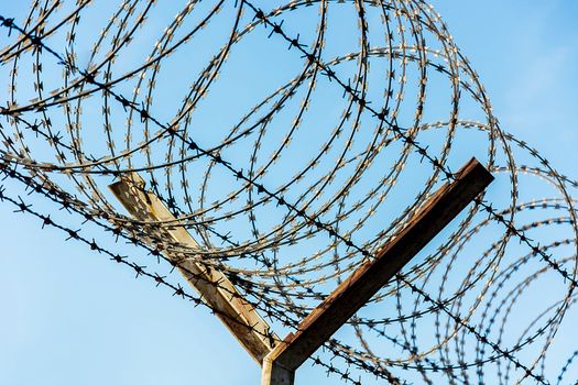 Barbed Wire Fence Used For Protection Purposes Of Property And Imprisonment, No Freedom, Barbed Wire On fence With Blue Sky To Feel Worrying.