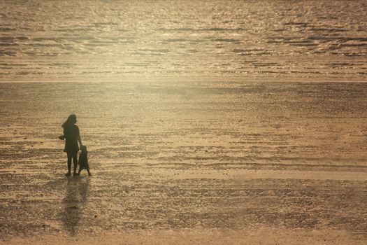 Silhouettes Of Mother And Son On Beach At Sunset.