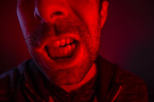 Man with angry facial expression screaming out loud. Close up portrait of a man shouting with mouth wide open.