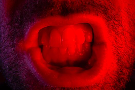 Man with angry facial expression. Macro close up portrait of a man with bared teeth.
