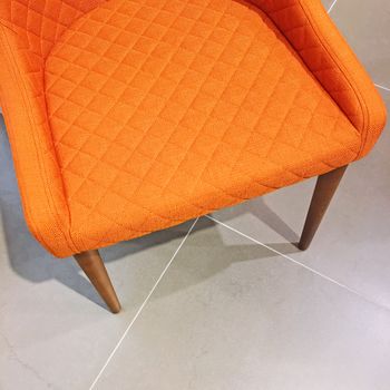 Bright orange armchair on tile floor. Modern style with a retro feel.