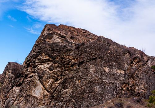 Red desert stone peak with blue sky and clouds