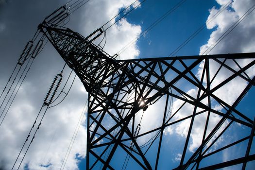 Power line tower taken at an unusual perspective with blue sky and clouds