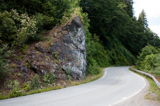 Curvy highway bending around a rocky corner with trees