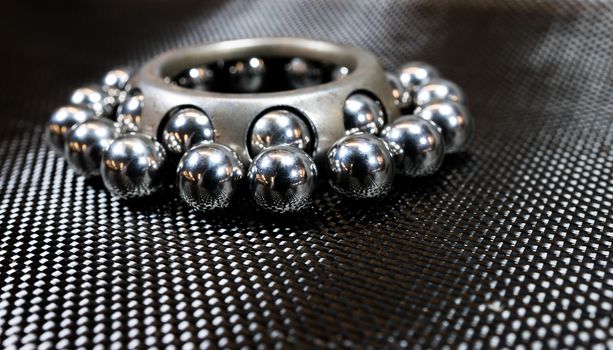 Loose ball bearings surrounding an automotive wheel bearing on carbon fiber cloth.