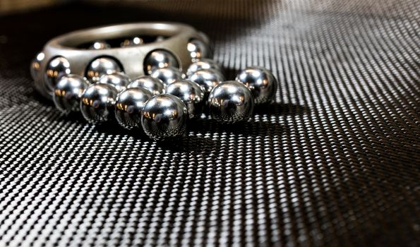 Loose ball bearings in front of an automotive wheel bearing on carbon fiber cloth.