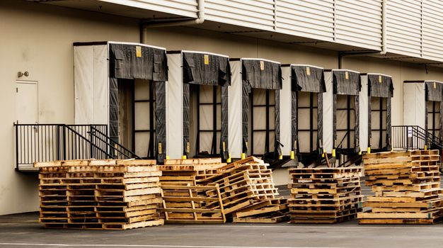 Warehouse truck bays with stacked wooden pallets in the foreground