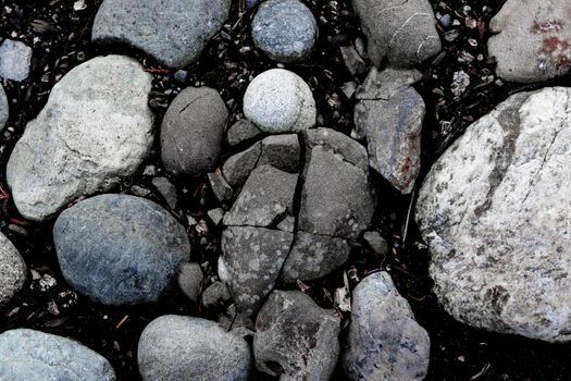 Round river rocks in the ground with a single cracked stone in the center