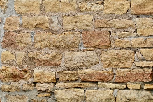 A wall made of Kasota stone was built in layers with cement and shows in the bright sun.