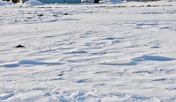 The rippling texture of snow drifts produced by high wind shows on the prairie.