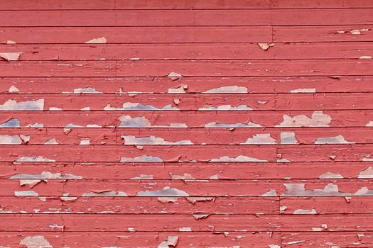 Horizontal rows of barn siding show with peeling red paint.