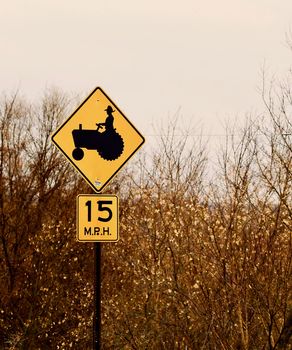 A yellow warning sign for tractors shows with a speed limit sign.