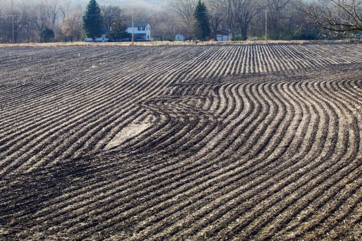 The stripes of a harvested and worked farm field show in the autumn.