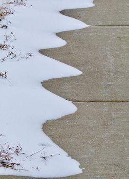 Snow drifts show their curves along the sidewalk.