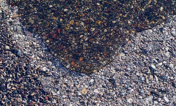Water slowly rolls across dry asphalt