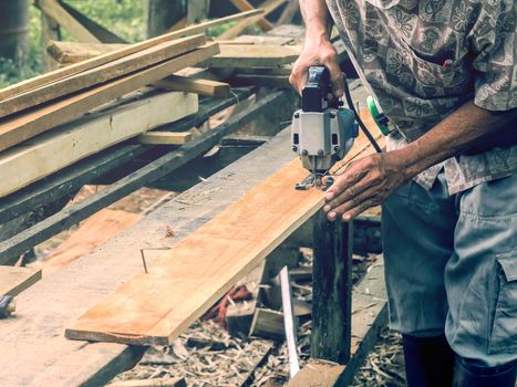 Carpenter cutting wooden panel by using jig saw