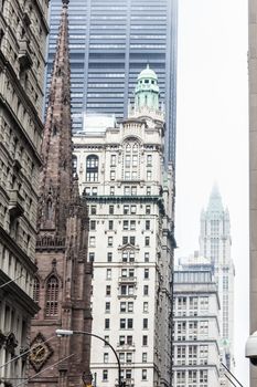New York City, Lower Manhattan, arhitectural detail of Broadway street wiev: Trinity Church, New York City Charter School Center and Woolworth building far away. Black and white vintage image.