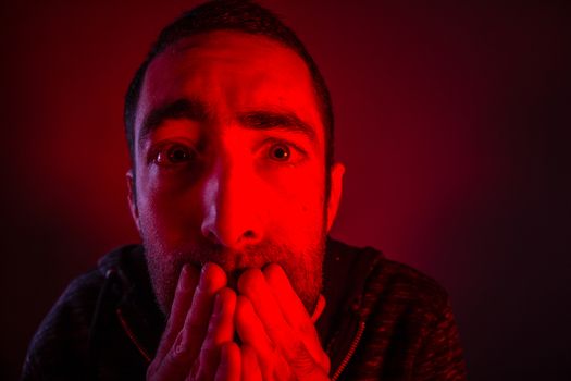 Stunned frightened man with surprised facial expression. Close up headshot portrait of shocked man with his hand on the face.