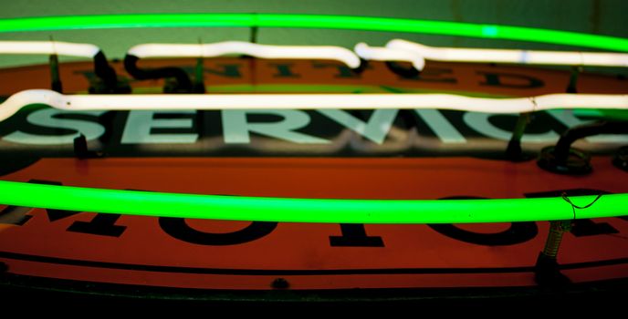 Close up of a green and white neon tubes on a sign with an orange background