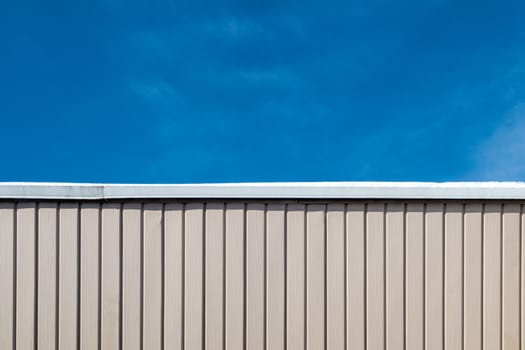 Half wall half blue sky . Top part of the picture is blue sky, bottom part is pink wall with patern lines.