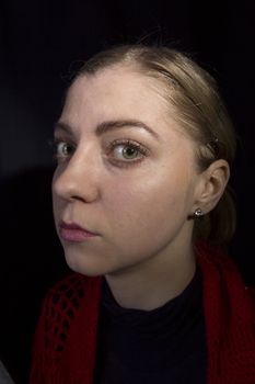 Strange young blonde woman close-up on a black background