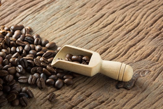 Pile of Fresh Raw Coffee Beans on Wooden Desk Table with Wooden Spoon as Refresh Beverages Concept.