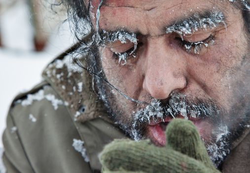 A close-up portrait of a freezing man, homeless, refugee, outdoors in a cold winter weather.