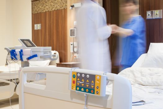 Blurred figures of doctor and a patient in modern hospital room.