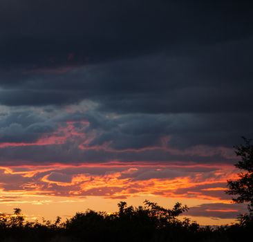 Dramatic clouds in orange, purple and black during sunset.