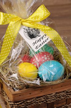 Colorful  eggs stacked hay in cellophane gift basket for Easter