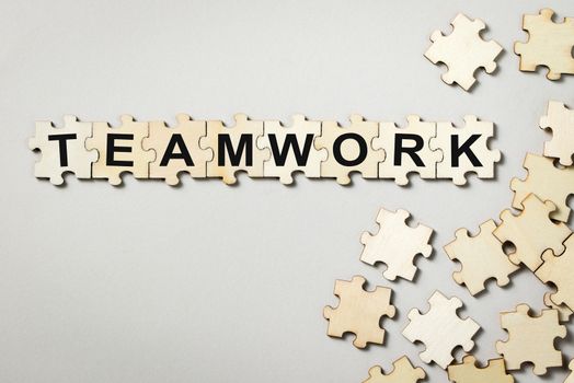 Jigsaw puzzle pieces with word teamwork on grey background