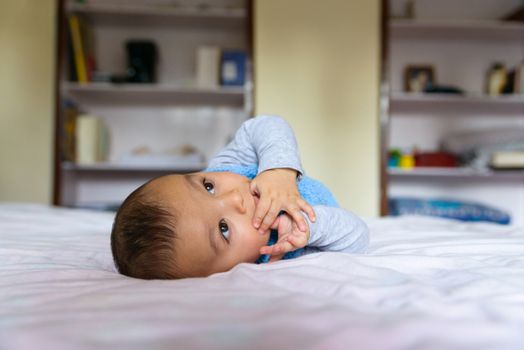 Eurasian baby lying on bed