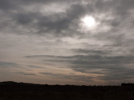 moody dark sky above field of grass sun setting autumn sun; essex; england; uk