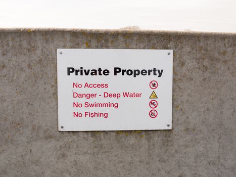 private property sign on grey sea wall barricade no permission; essex; england; uk