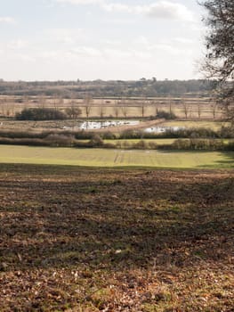 view of large valley with lake river and row of trees in the distance outside; essex; england; uk