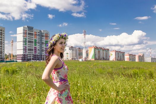 Portrait of the beautiful girl in the field against the background of the city