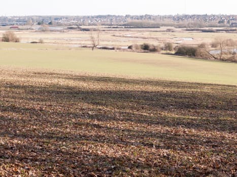 view of large valley with lake river and row of trees in the distance outside brown texture floor; essex; england; uk