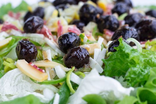Green salad with vegetables, olives, cabbage, onions, sausages for healthy fitness slim diet close-up