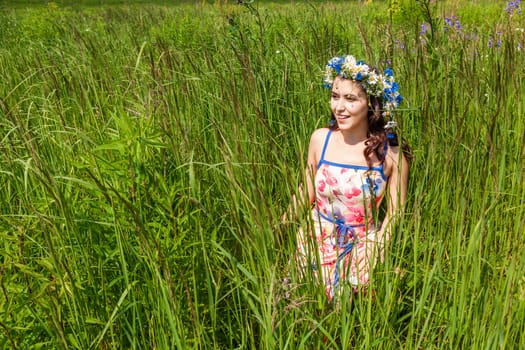 Portrait of the beautiful girl in the field in flowers