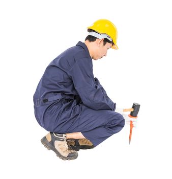 Young man in uniform sit and holding hammer was nailed to a cold chisel, Cut out isolated on white background