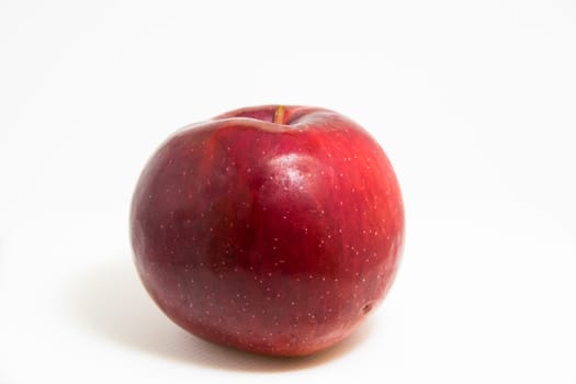 Natural red apple isolated on white, bright smooth red skin and tiny white dots.