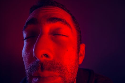 Man with peaceful calm facial expression with close eyes. Close up portrait of meditating and thinking young man looking at camera.