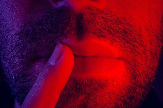 Macro close up on man with thoughtful facial expression with his finger to his lips. Portrait of thinking young man.