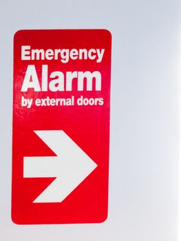 close up of red sign with direction emergency alarm by external sign inside train; essex; england; uk